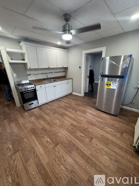 A kitchen with wooden floors and a refrigerator with a yellow sticker on it.