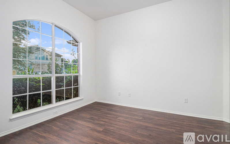 A room with a dark floor and a white wall with a window.