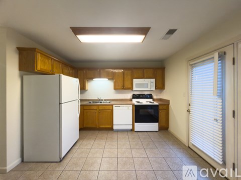 A kitchen with white appliances and wooden cabinets.