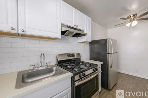 A kitchen with a stove, sink, and refrigerator.