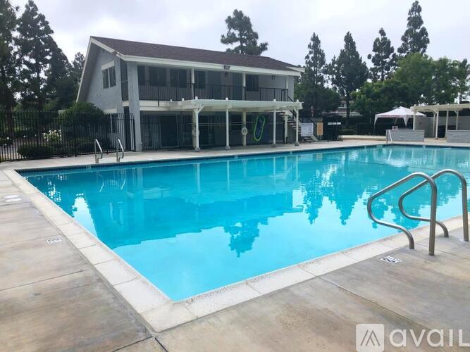 A swimming pool in front of a house with a pool house attached.