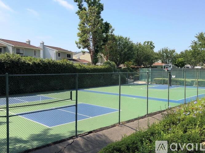 A tennis court surrounded by a fence and trees.
