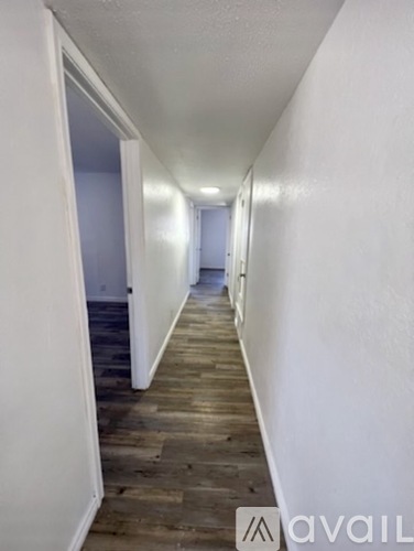 A long hallway with wood floors and white walls.