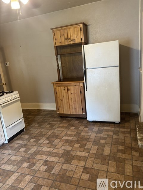 A kitchen with a white fridge, a white stove and a wooden cabinet.