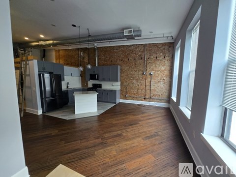A kitchen with wooden floors and a brick wall.