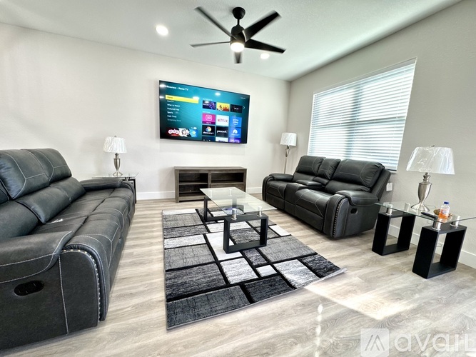 A modern living room with black leather furniture and a flat screen TV mounted on the wall.