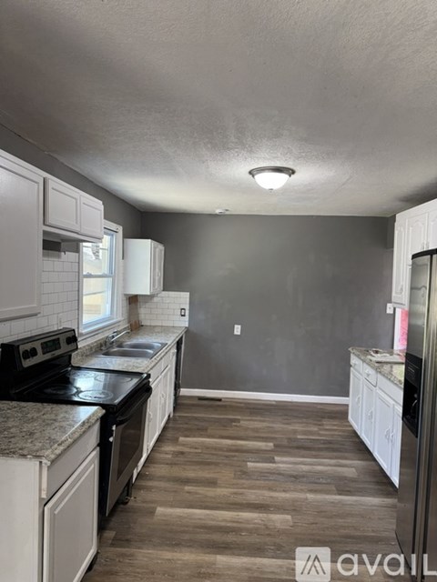 A kitchen with white cabinets and a black stove top oven.