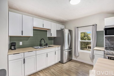 A kitchen with white cabinets and a green backsplash.