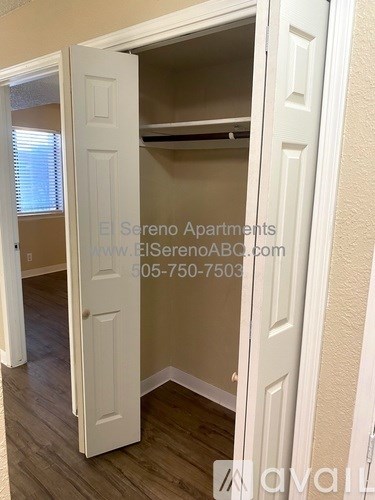 A white door is open to reveal a small bedroom with a bed and a closet.