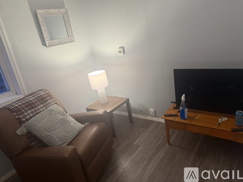 A living room with a brown couch, a small table with a lamp, and a flat screen TV.