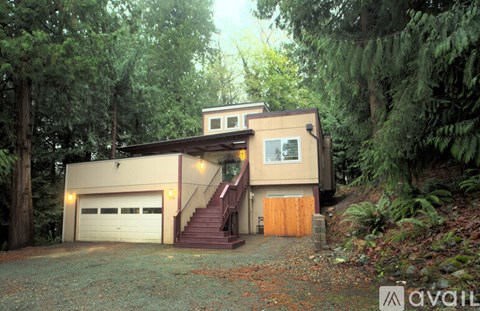 A house with a garage is surrounded by trees.