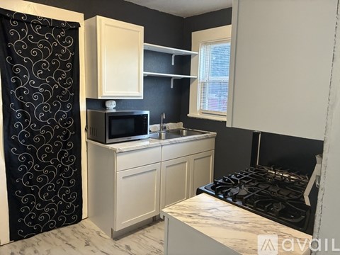 A kitchen with a black stove top oven and a black and white patterned shower curtain.