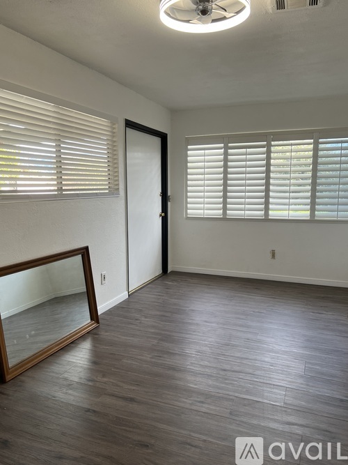 A room with wooden floors and a large mirror on the wall.