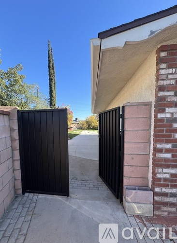 A black gate is closed in front of a house.