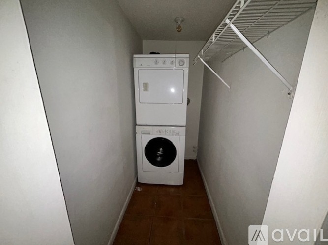 A kitchen with white appliances and brown tile flooring.