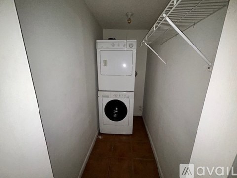 A kitchen with white appliances and brown tile flooring.
