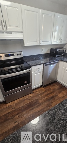 A spacious, empty room with a kitchen area visible through the doorway.