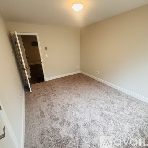 A room with a carpeted floor and a doorway leading to another room.