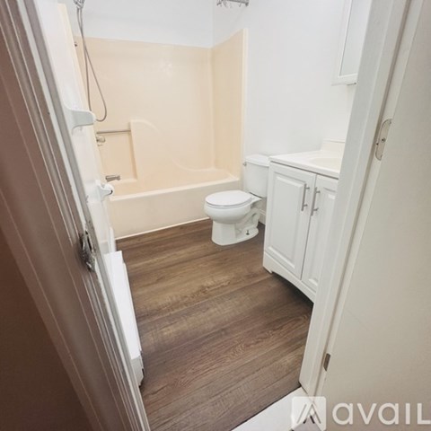 A white door is open to a kitchen with a fridge and dishwasher.