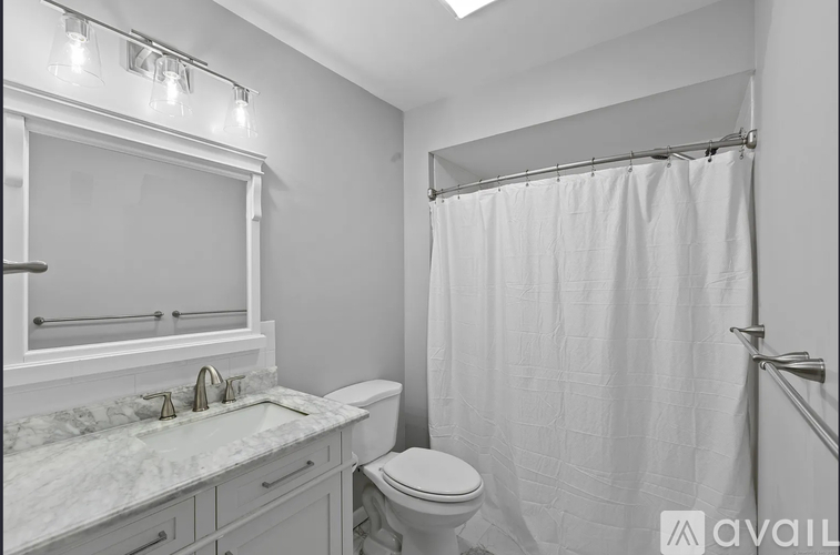 A bathroom with a marble countertop and white fixtures.