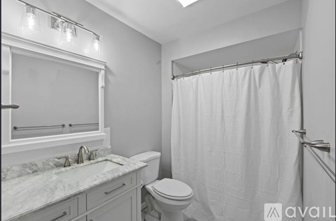 A bathroom with a marble countertop and white fixtures.