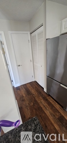 A spacious room with wood flooring and white walls.