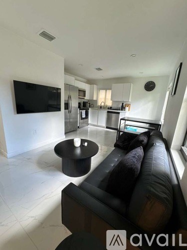 A living room with a black couch and a television mounted on the wall.