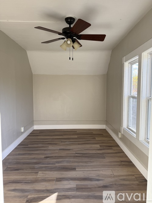 A room with a ceiling fan and wooden flooring.