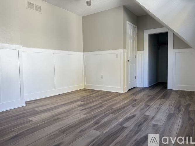 A room with wooden flooring and white walls.