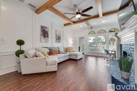 A spacious living room with a white sofa and wooden flooring.