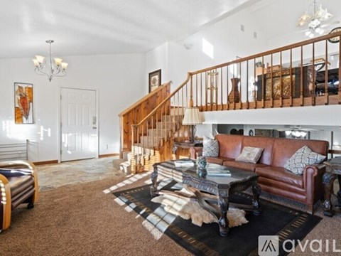 A living room with a brown leather couch and a black and white checkered rug.