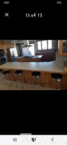 A kitchen with wooden cabinets and a bar area with stools.