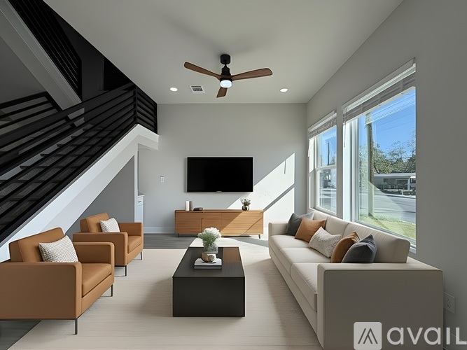 A living room with a staircase and a flat screen TV.