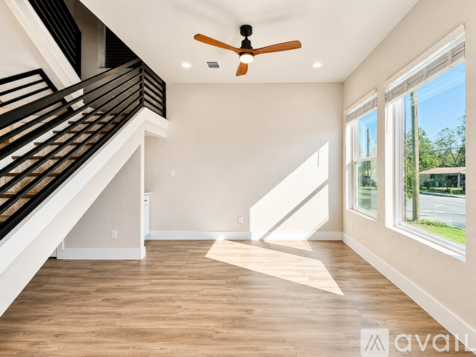 A spacious room with a ceiling fan and a staircase leading to the upper floor.