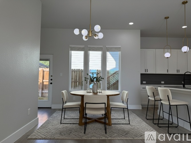 A dining room with a table set for four and a kitchen area in the background.