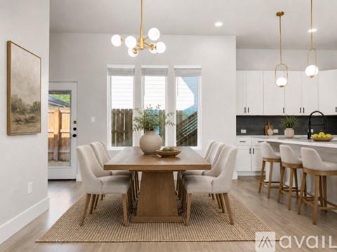 A dining room with a table set for four and a kitchen area in the background.
