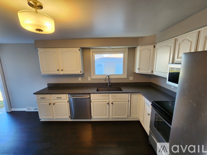 A kitchen with white cabinets and black countertops.