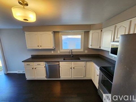 A kitchen with white cabinets and black countertops.