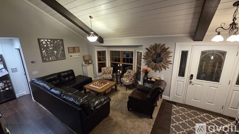 A living room with a black leather couch and a wooden coffee table.