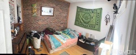A bedroom with a bed, a couch, and a green tapestry hanging on the wall.