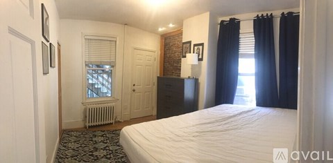 A bedroom with a large bed and a window with black curtains.
