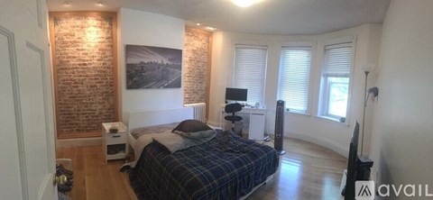 A bedroom with a brick wall and a bed.