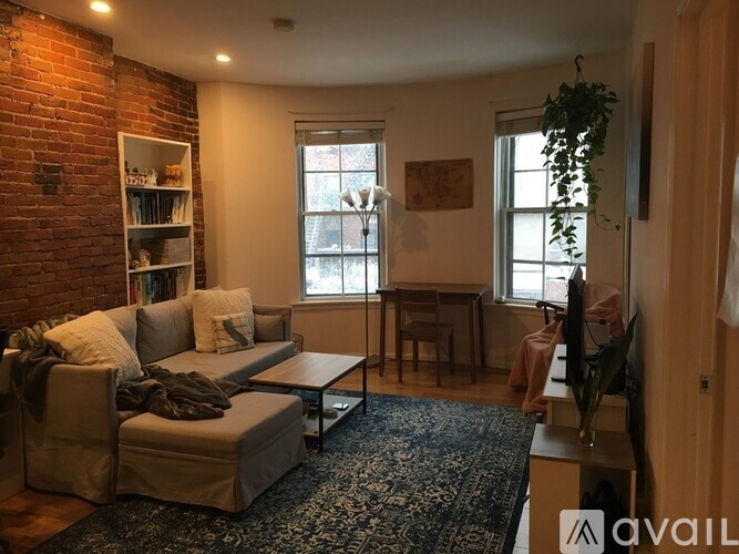 A living room with a brick wall and a grey couch.