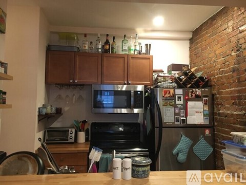 A kitchen with a brick wall and a refrigerator with magnets on it.