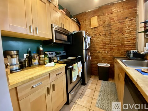 A kitchen with wooden cabinets and a black refrigerator.