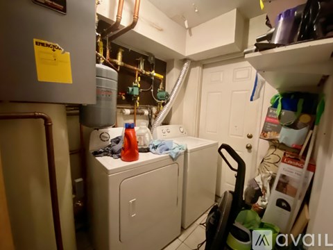 A laundry room with a washer and dryer, a yellow sticky note on the wall, and a black vacuum cleaner.
