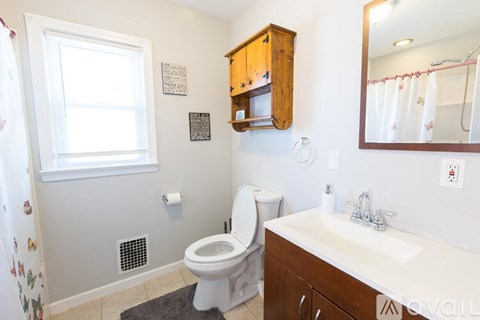 A bathroom with a toilet, sink, and a mirror.