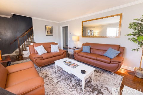 A living room with a brown leather couch, a white coffee table, and a mirror on the wall.
