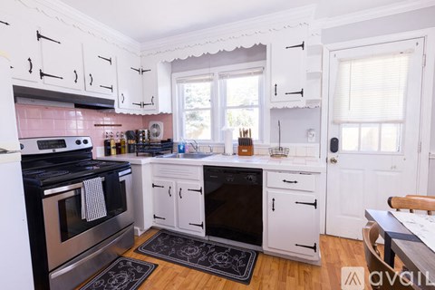 A kitchen with white cabinets and black and white rugs.