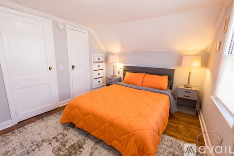 A bedroom with a bed covered in an orange comforter.